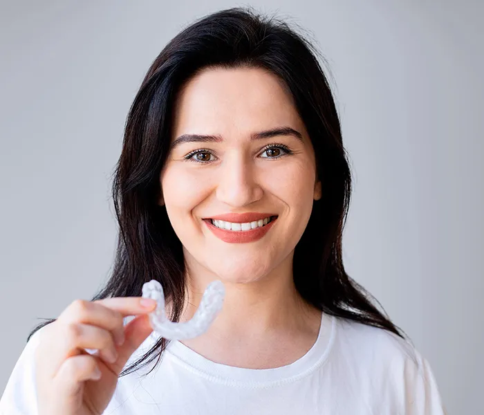 Invisalign 2 Invisalign - Smiling woman holding clear aligner at a trusted dentist in Bellingham.