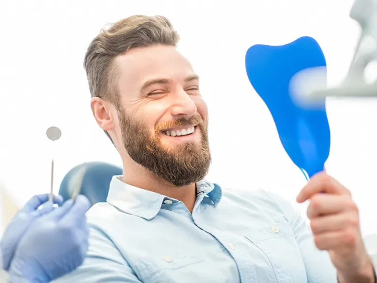Dental Cleaning 3 Smiling man in dental chair holding a mirror after treatment with a cosmetic dentist in Bellingham.