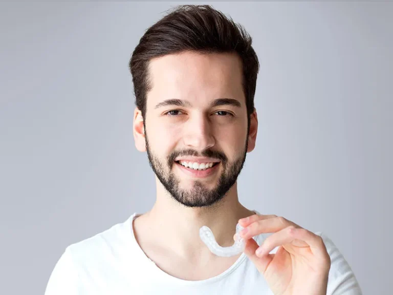 Invisalign 8 Man smiling while holding clear aligner from trusted local dentist in Bellingham.