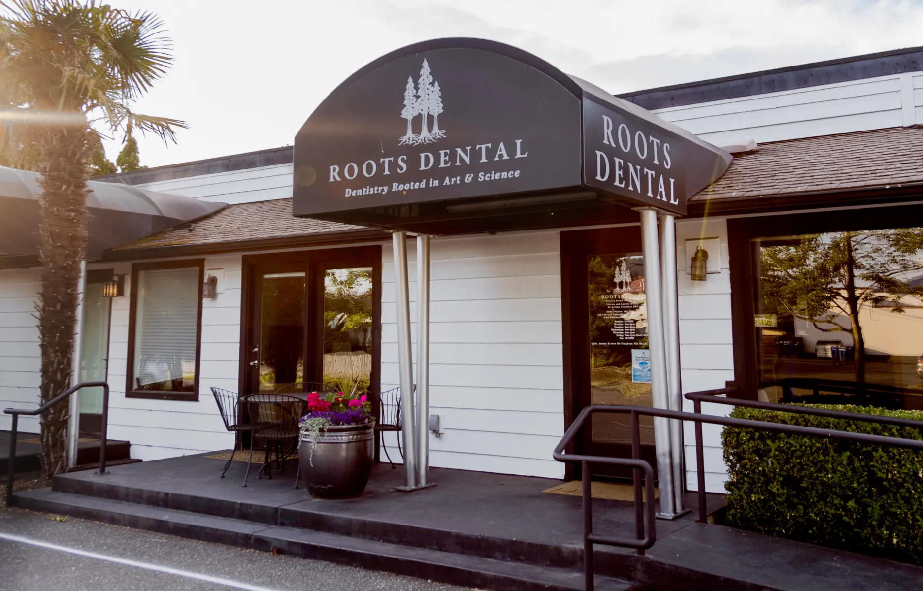 Your Dentist in Bellingham, WA | Roots Dental - Front entrance of Roots Dental clinic in Bellingham with signage, seating, and welcoming flowers.