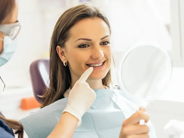 Single Implants 2 Female patient checking her smile during consultation at cosmetic dentist in Bellingham.