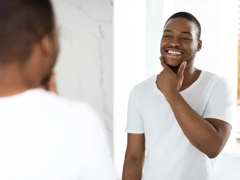 Facial Injections 2 Young man smiling in mirror after care from family dentist in Bellingham at Roots Dental.