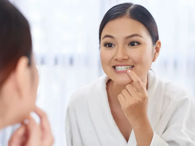 Veneers 3 Woman examining her teeth in mirror after care from a cosmetic dentist in Bellingham.