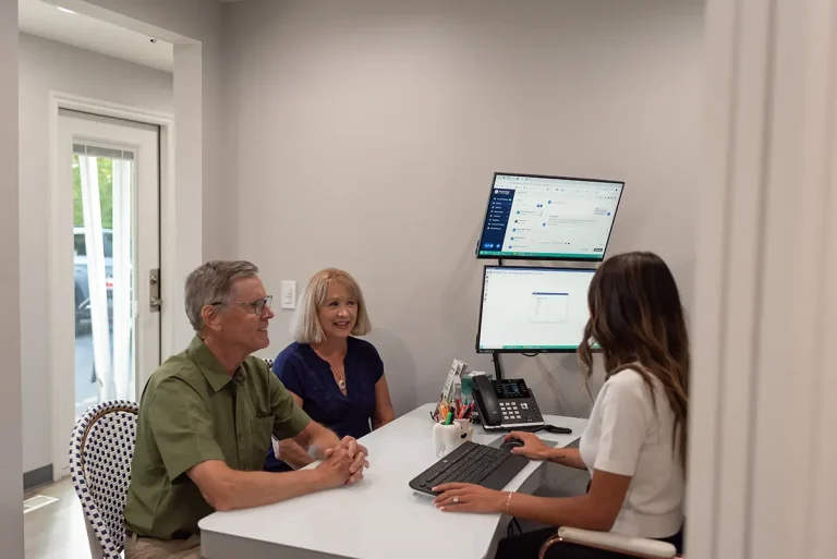 Insurance 2 Dental team member at Roots Dental in Bellingham, WA discussing treatment options with two patients during a private consultation.