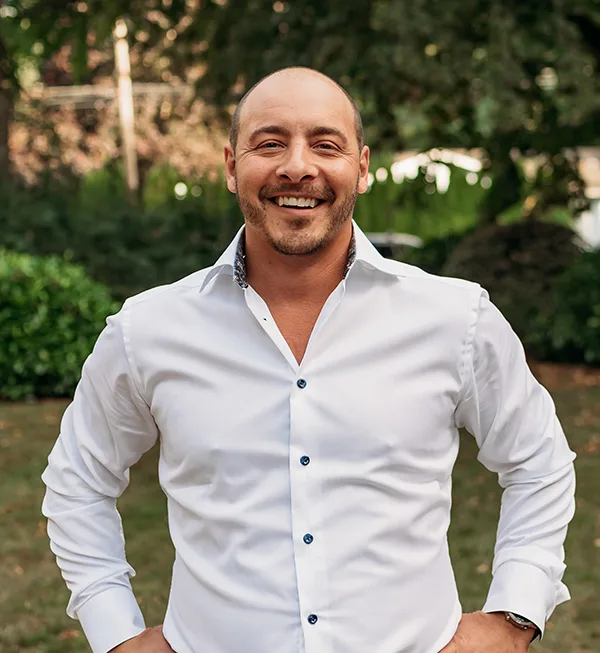 Dr. Joshua Clarkman, dentist at Roots Dental in Bellingham, smiling in a professional outdoor portrait.