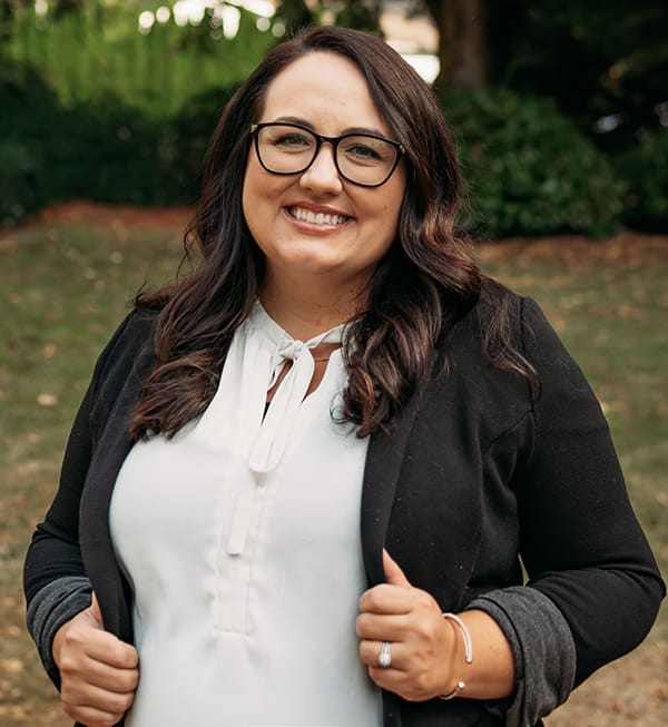 Meet the Doctor 2 Female Roots Dental team member in Bellingham with glasses, smiling outdoors.