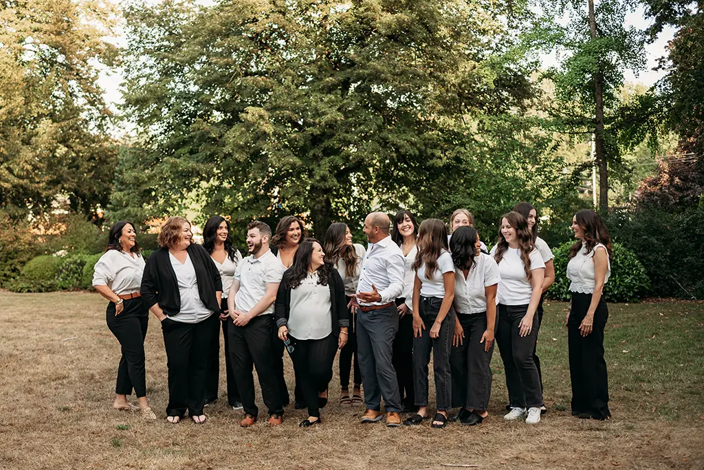 Meet the Doctor 17 Candid group photo of Dr. Joshua Clarkman and the Roots Dental team in Bellingham, WA, smiling and laughing outdoors.