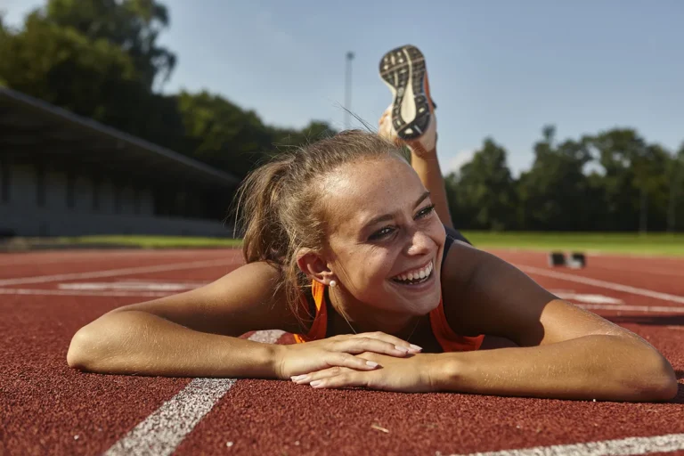 Smiling runner lying on race track | dental cleaning Bellingham WA